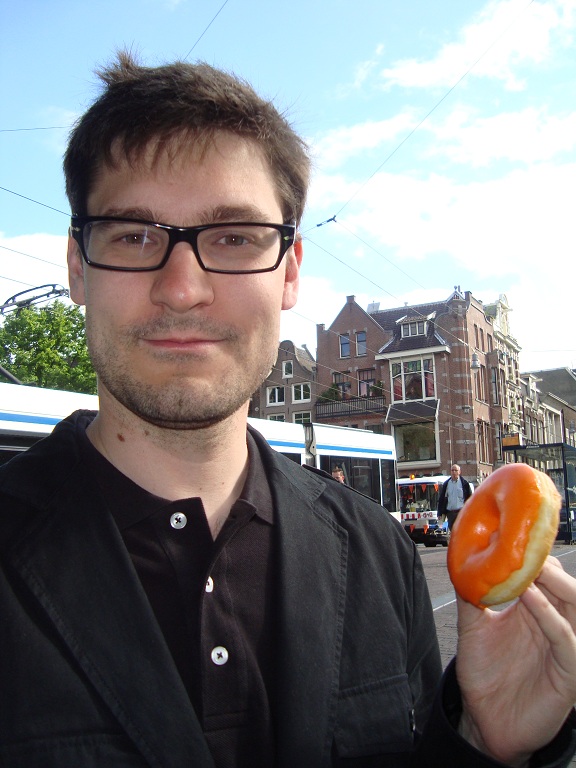 That's me in Amsterdam, half-awake and really happy to have an orange doughnut for breakfast